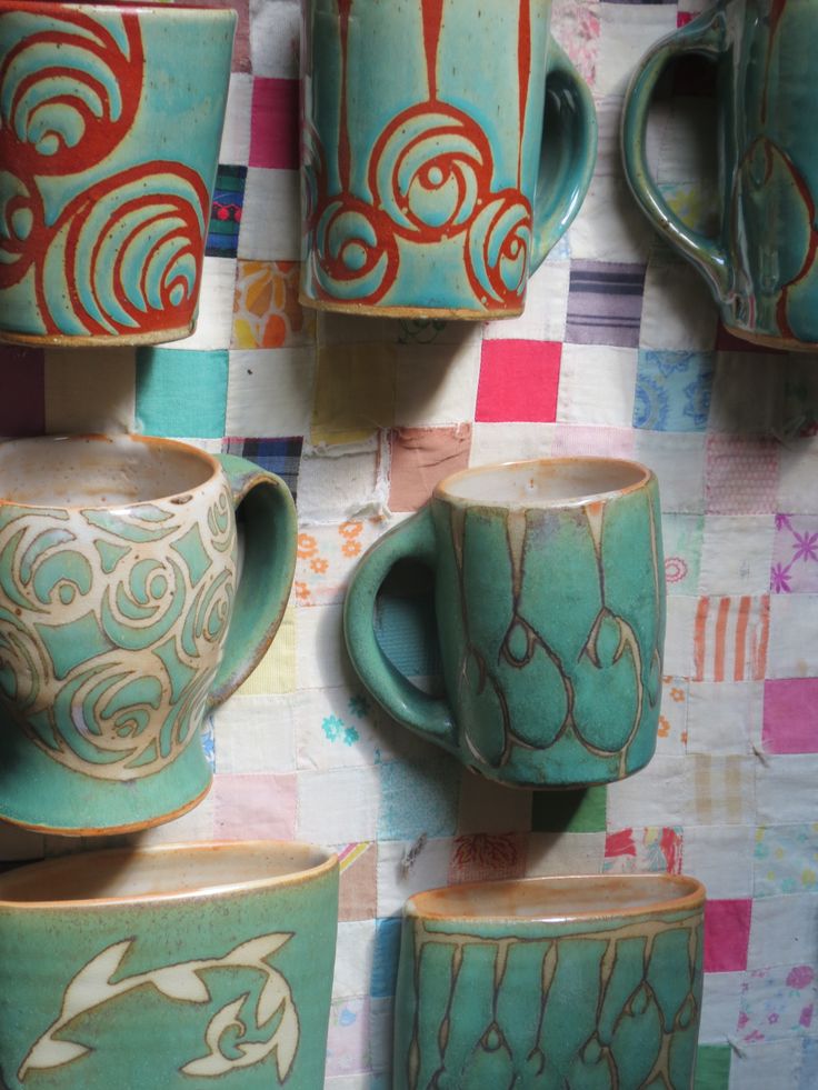 tea cups and saucers on display in a room with colorful wall paper behind them