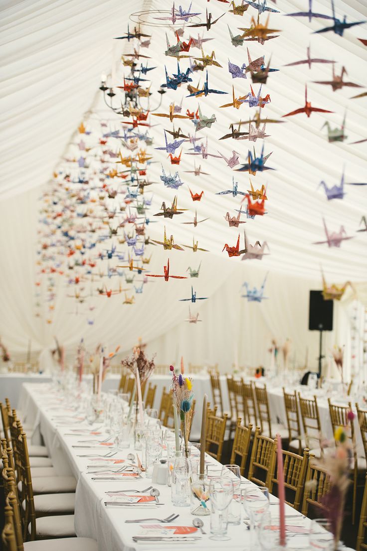 a long table with many paper airplanes hanging from it's ceiling in a marquee