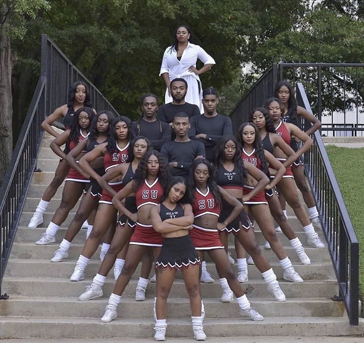 a group of cheerleaders posing for a photo on the steps with their coach