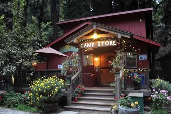 the entrance to camp store is lit up with lights and potted plants on either side