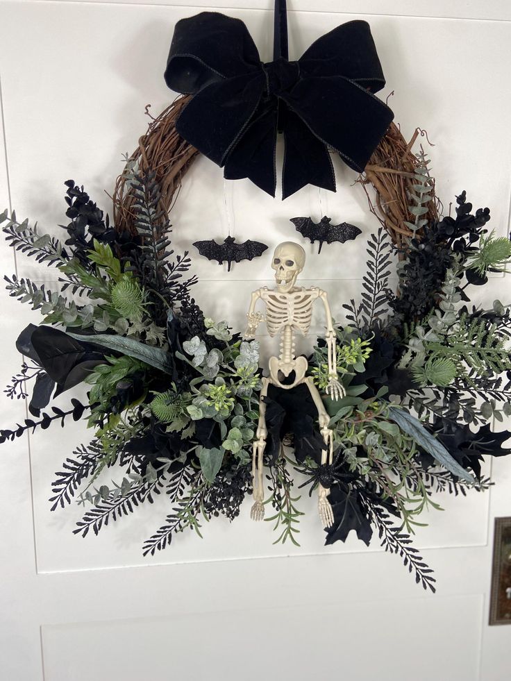 a wreath with a skeleton in the middle and greenery around it, hanging on a door