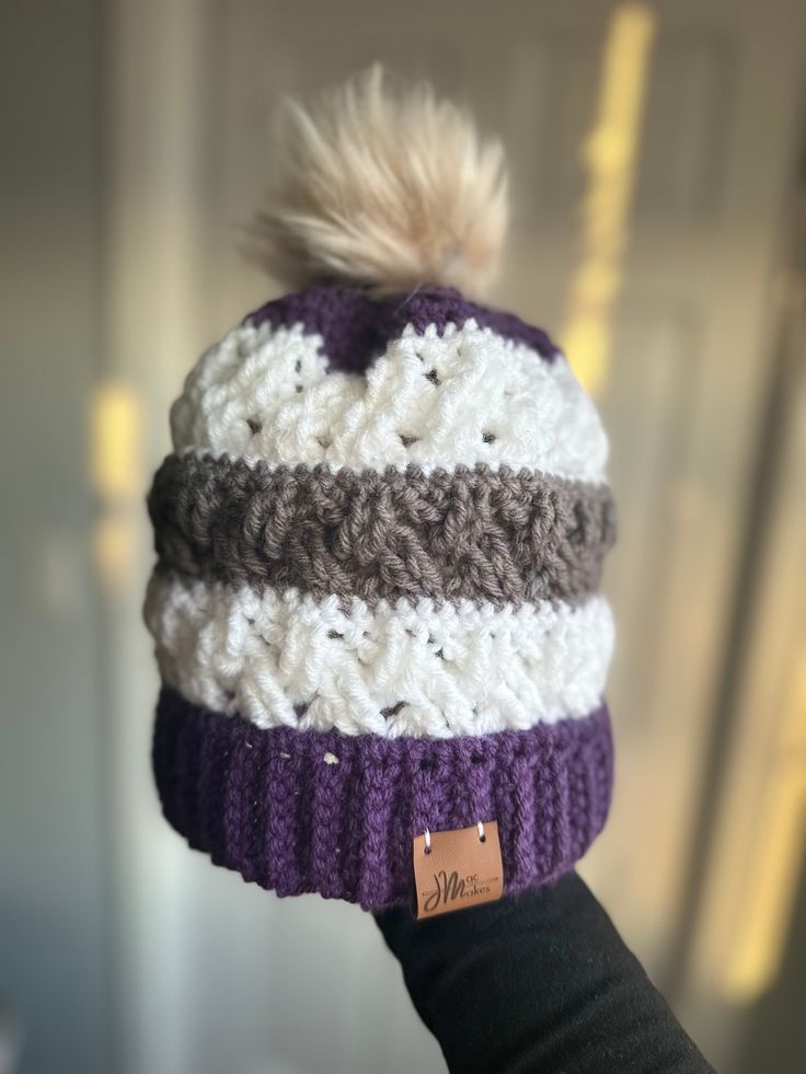 This super comfy beanie is exactly what you need this winter! The hats are crocheted and made with 100% acrylic yarn.  The purple, white, and gray hat fits a large child/small adult head. It is 7.5" tall when laid out, 10" with the pom pom included. It is also stretchy. The pom pom is faux fur. This hat was created based on the pattern found at this link: https://www.crochetforyoublog.com/2023/09/crochet-celtic-stripes-beanie/. Please contact me with any questions! Purple Hand Knitted Beanie, White Adjustable Beanie For Cold Weather, White Acrylic Beanie One Size, Purple Crochet Beanie Hat, Hand Knitted Purple Crochet Beanie, Purple Yarn Crochet Hat, Hand-knitted Purple Crochet Beanie, Purple Crochet Beanie For Winter, Purple Hand Knitted Crochet Beanie