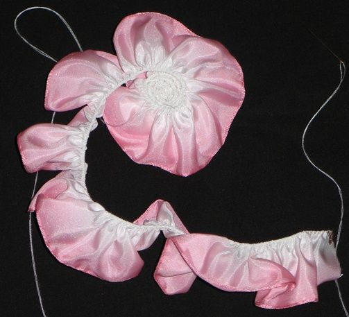 two pink flowers are attached to the side of a headband on a black background