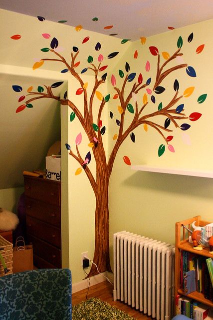 a living room with a tree painted on the wall and a radiator next to it