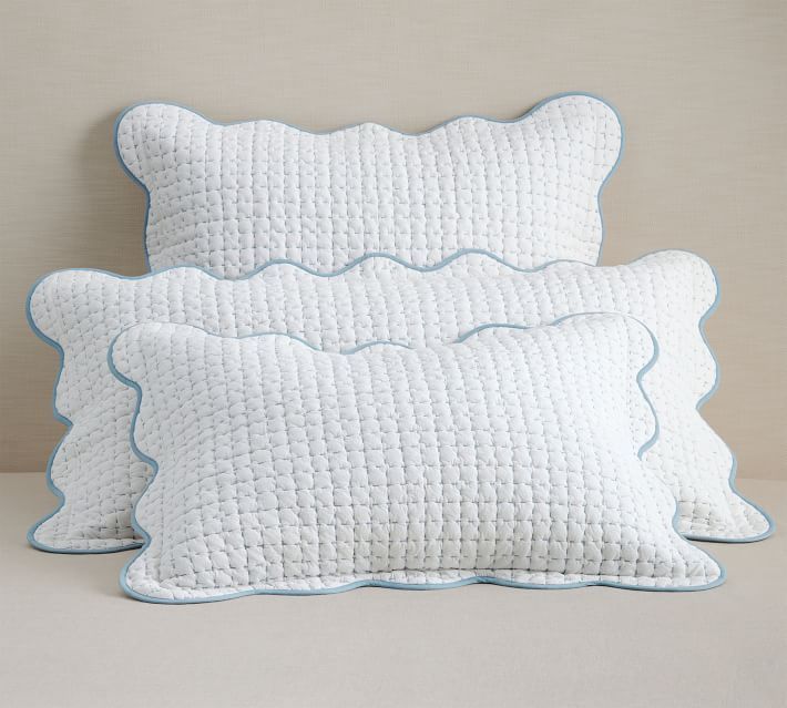 two pillows sitting on top of each other in front of a white wall with blue trim