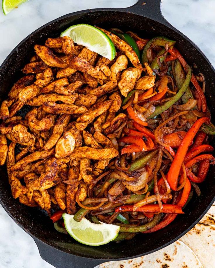 chicken fajitas in a skillet with lime wedges