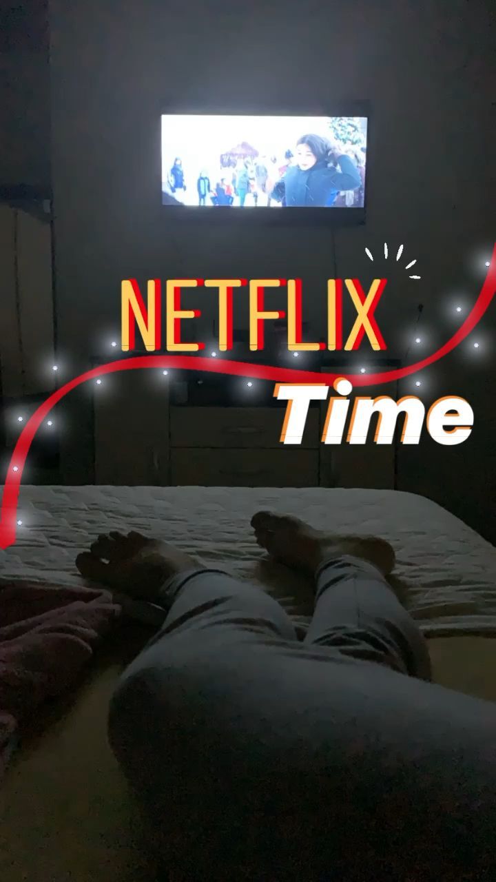 a person laying on a bed with their feet up in front of a television that reads netflix time