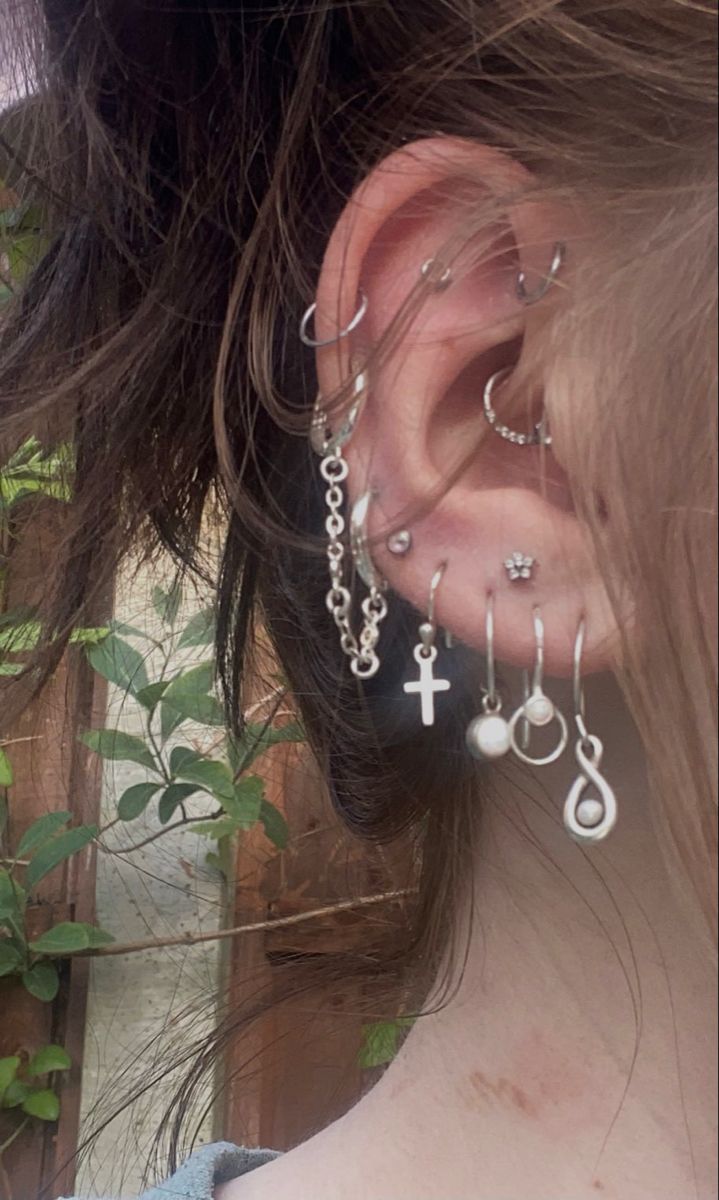 a close up of a person's ear with cross and beads attached to it