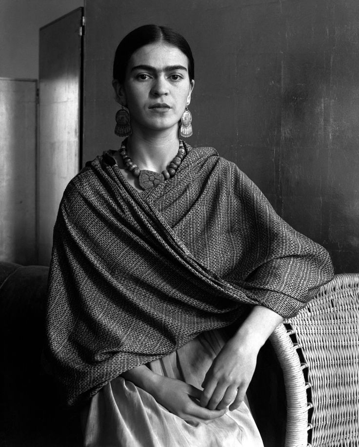 an old photo of a woman sitting in a chair with a shawl over her shoulders