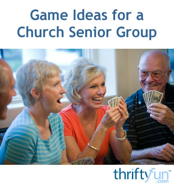 a group of people sitting around each other holding cards and playing games for a church senior group