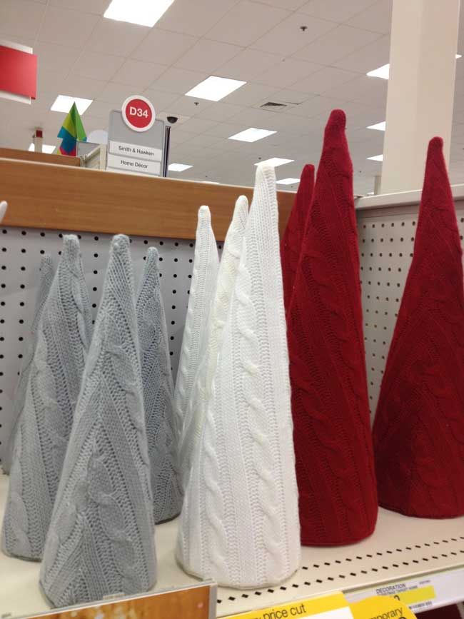 three knitted christmas trees are on display in a department store, with price tags below them