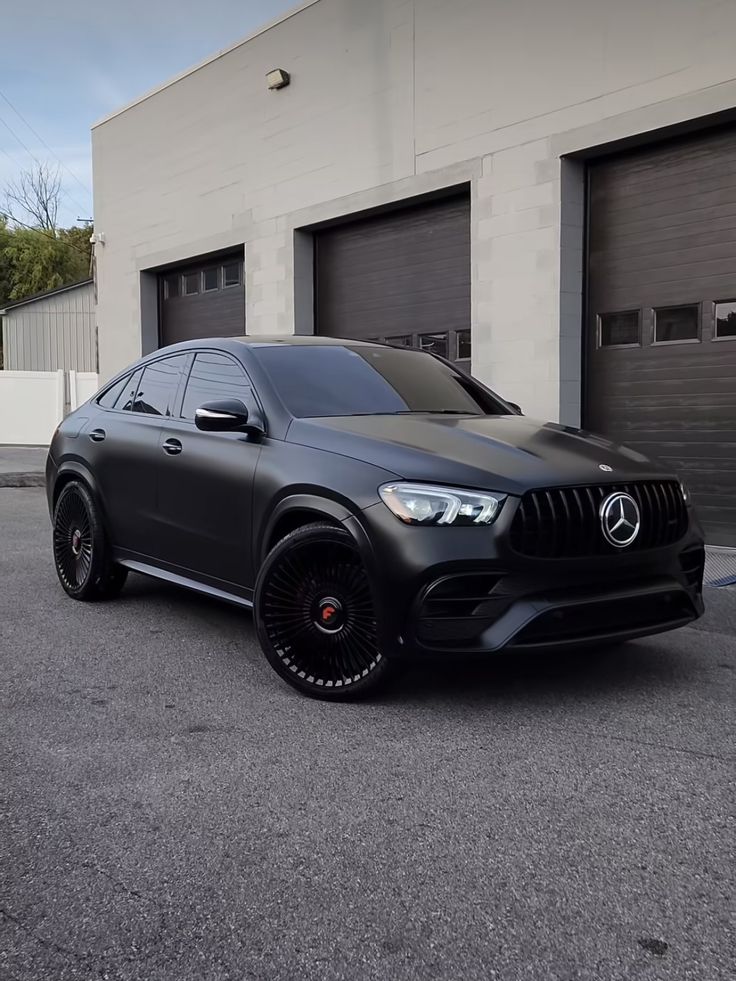 a black mercedes suv parked in front of a garage