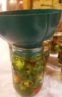 a jar filled with pickles sitting on top of a table next to other jars