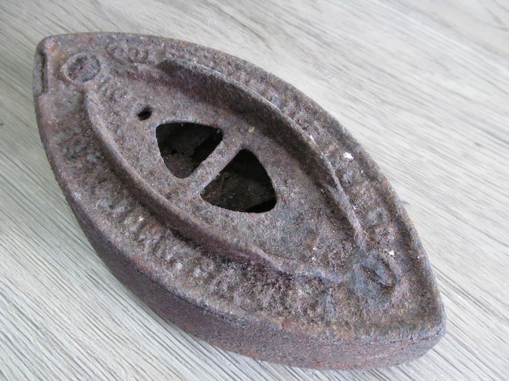 an old metal object sitting on top of a wooden table with holes in it's center