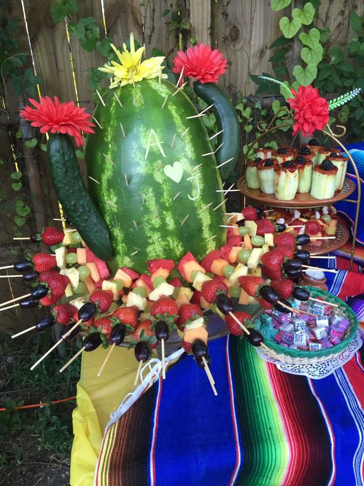 a table topped with lots of fruits and vegetables next to cupcakes on skewers