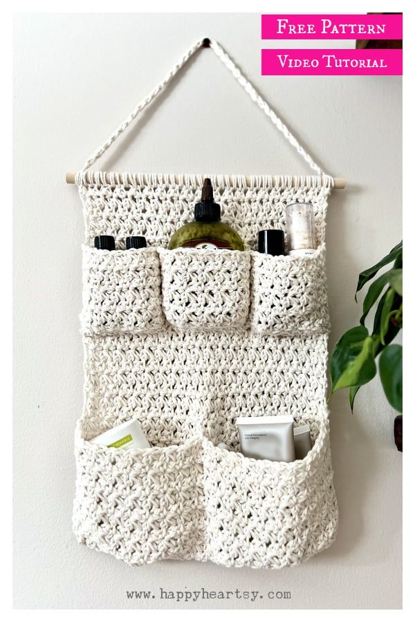 a crocheted wall hanging with two pockets for cosmetics and toiletries in it