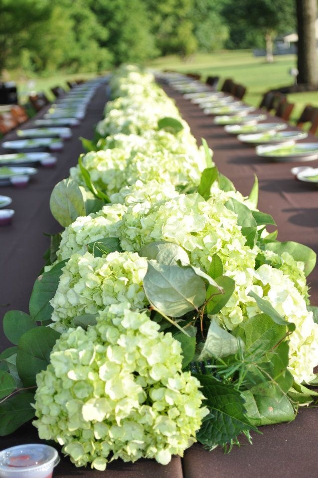 there is a long table with many plates on it and flowers in vases next to the tables