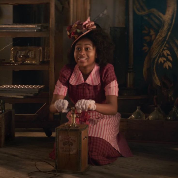 a woman sitting on the floor in front of a wooden box with an object inside