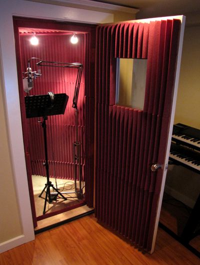 an empty room with a piano and sound equipment in the corner, while lights shine brightly on the wall