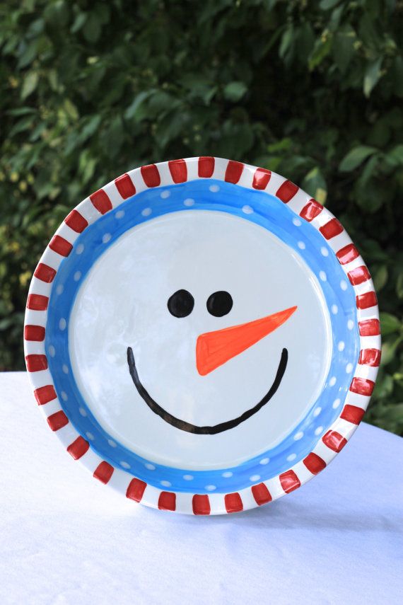 a snowman plate sitting on top of a white tablecloth covered table with trees in the background