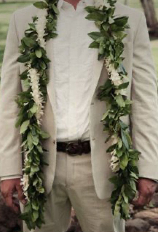 a man wearing a white suit and flower lei around his neck