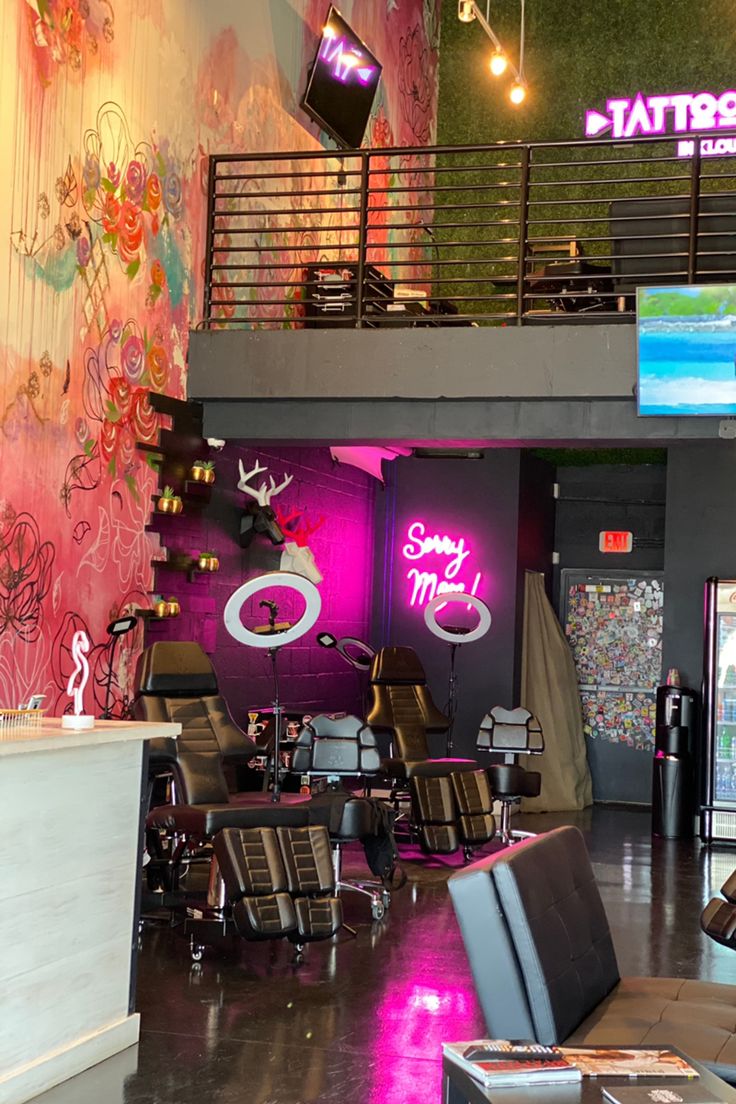 the interior of a hair salon with chairs and neon signs on the wall behind it