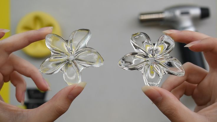 two hands are holding clear glass flowers