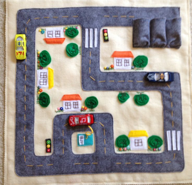 a child's play mat with cars, houses and trucks on the road made out of felt