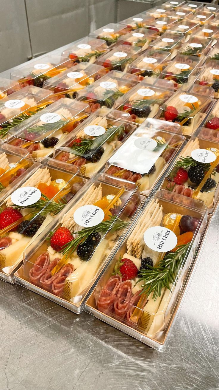 many different types of cheeses and fruits in plastic trays on a counter top