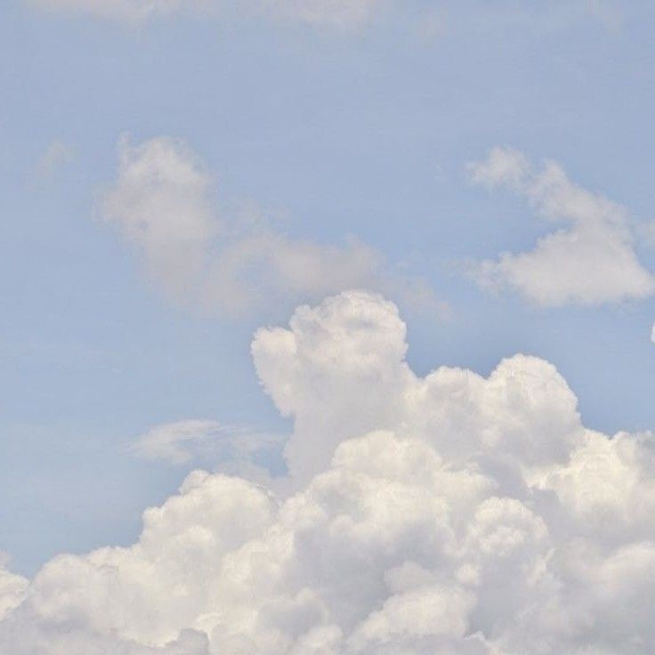 the airplane is flying high in the sky with white clouds behind it and blue skies above