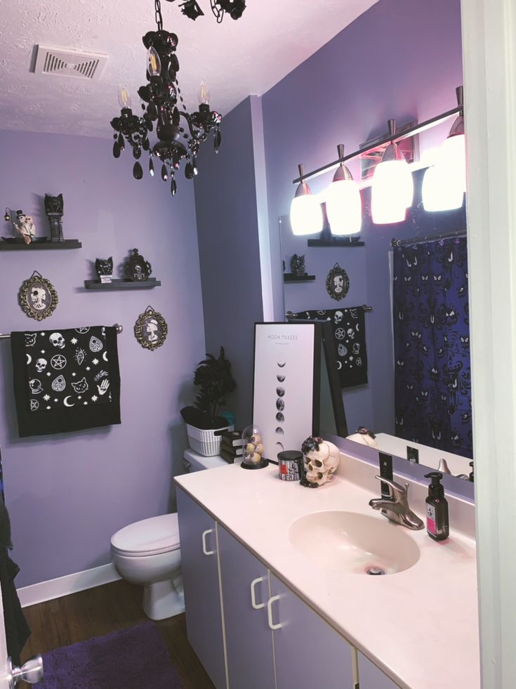 a bathroom with purple walls and white counter tops, decorated with black and silver decorations