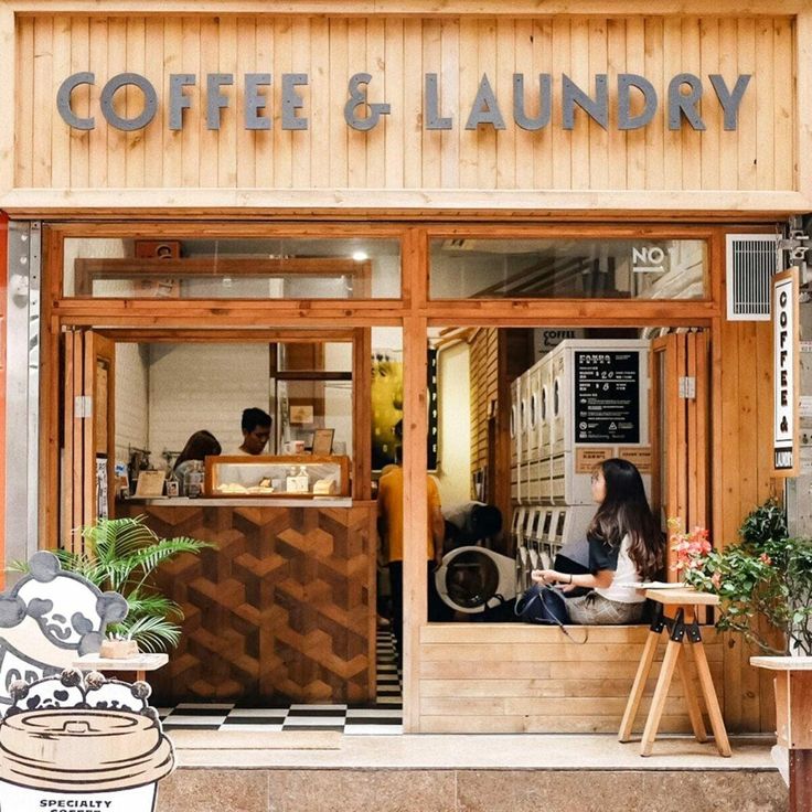 people sitting at tables in front of a coffee and laundry shop