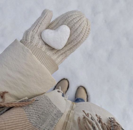 someone wearing mittens and gloves with a white heart on their thumb, in the snow