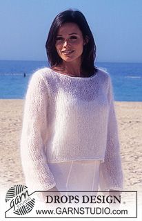 a woman standing on top of a sandy beach next to the ocean with her hands in her pockets