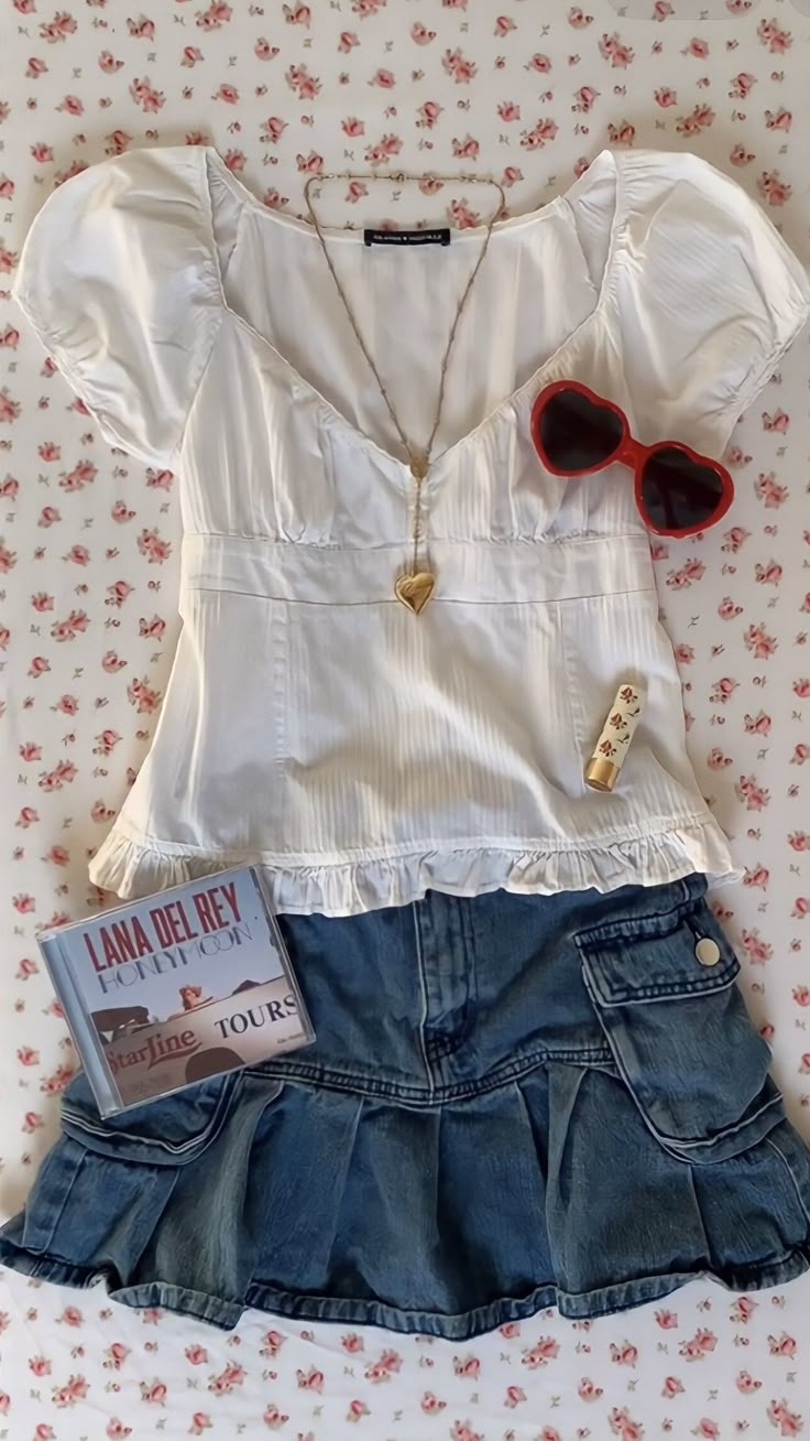 a white shirt and blue jean skirt with red sunglasses on top of a floral print bed spread