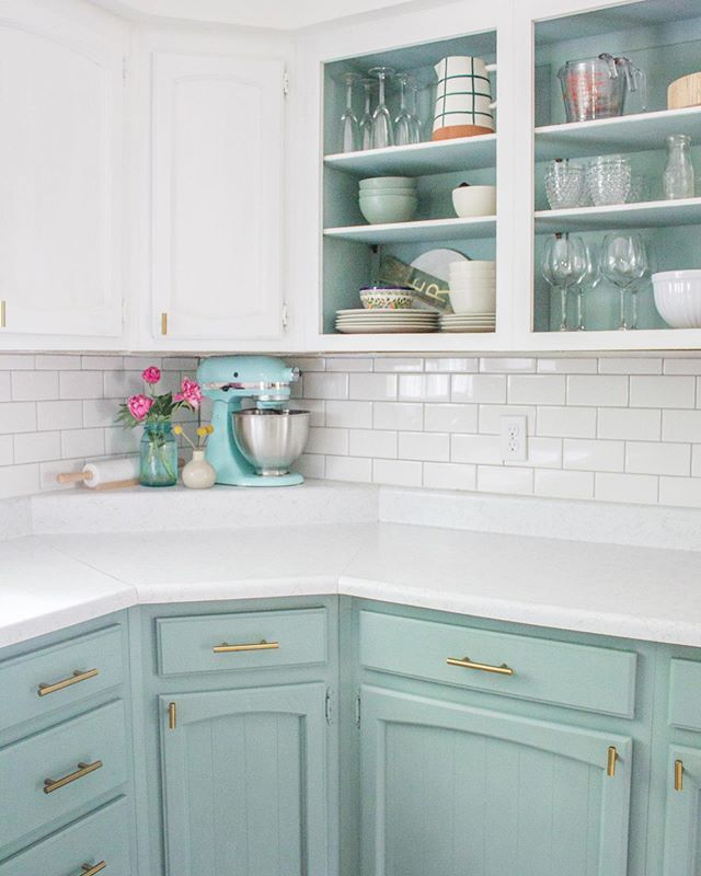 a kitchen with blue cabinets and white counter tops is pictured in this image, there are dishes on the shelves