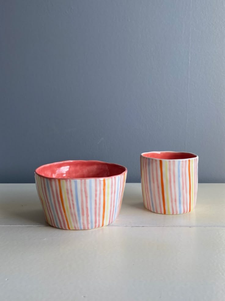 two bowls sitting on top of a table next to each other, one with a striped design