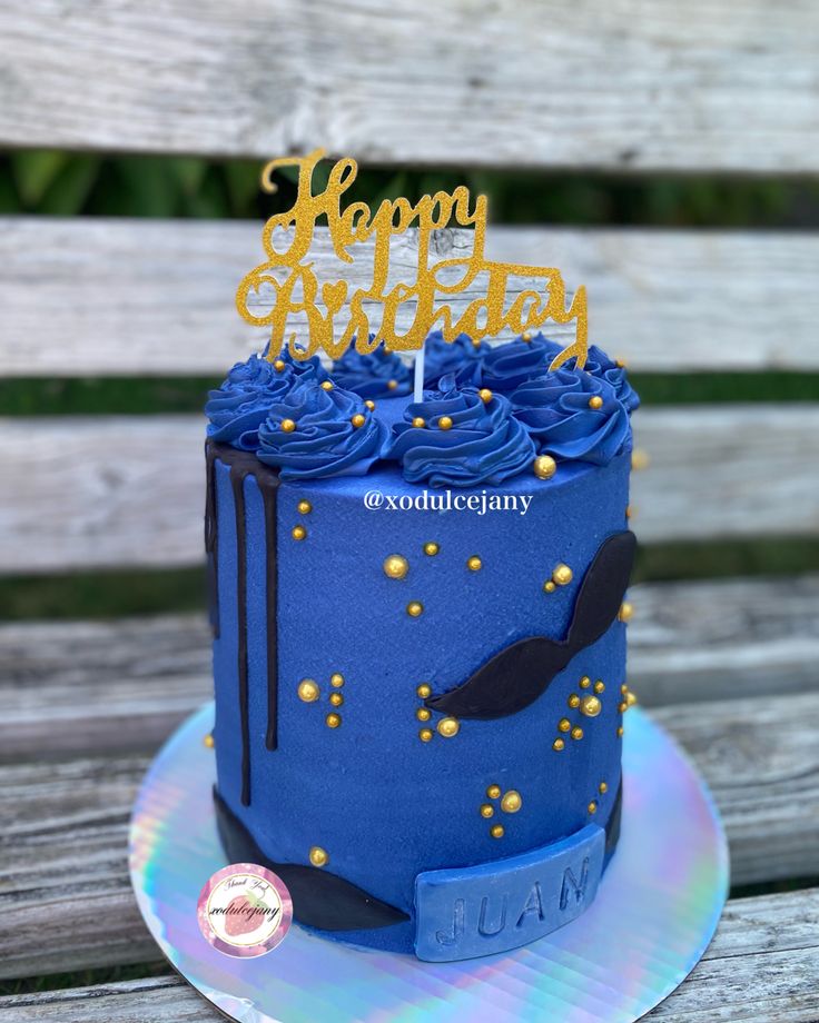 a birthday cake with blue frosting and gold sprinkles sits on a wooden table