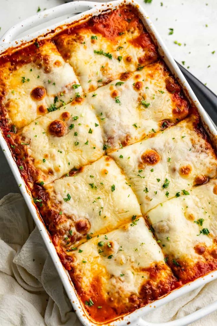 a casserole dish with cheese and sauce on the side, ready to be eaten