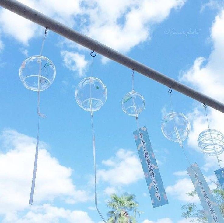 some bubbles hanging from a metal pole with palm trees and blue sky in the background