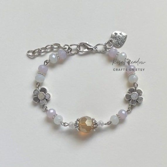 "A handmade bracelet ✿ Made with glass crystal beads and metal accents ✿ Milky white, pastel pink, dusty yellow, and silver ✿ The bracelet has an additional 1-1.5\" of extension chain" Adjustable Crystal Bracelet For Jewelry Making, Handmade White Beaded Metal Bracelets, Handmade White Beaded Metal Bracelet, Silver Czech Glass Crystal Bracelet For Jewelry Making, Silver Czech Glass Crystal Bracelet As Gift, Silver Crystal Bracelet With Czech Glass For Gift, Silver Crystal Bracelet With Czech Glass As Gift, Adjustable White Metal Crystal Bracelet, White Beaded Metal Crystal Bracelet