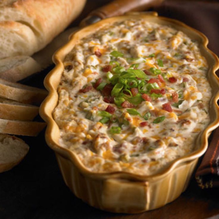 a bowl of dip with bread in the background