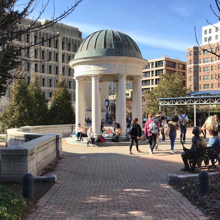 people are walking around in the park near some buildings and a gazebo with a dome on top