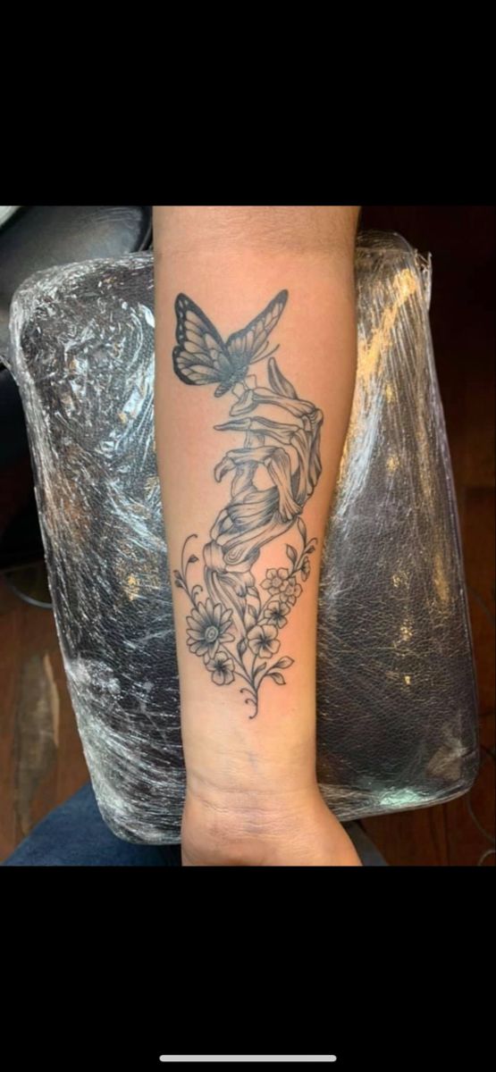 a woman's arm with a tattoo on it that has flowers and a butterfly