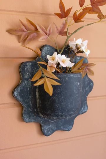 a potted plant with white flowers hanging on a wall