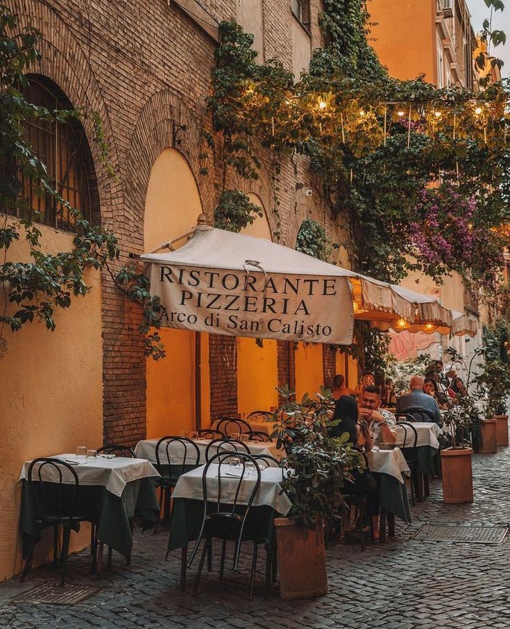 an outdoor restaurant with tables, chairs and umbrellas on the side of a street