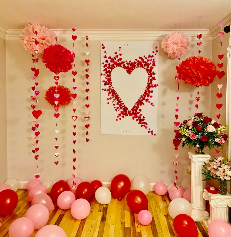 valentine's day decorations with balloons and flowers on the wall, along with paper pom poms