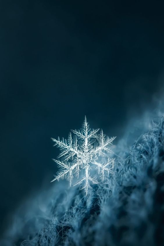 a snowflake is shown in the middle of blue and black sky with clouds