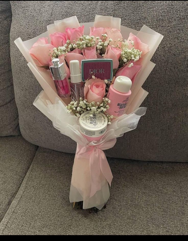 a bouquet of pink roses and baby's breath in front of a gray couch