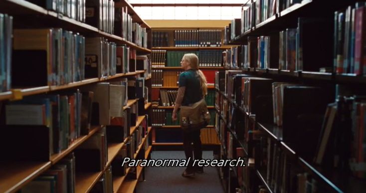 a woman standing in the middle of a library filled with books